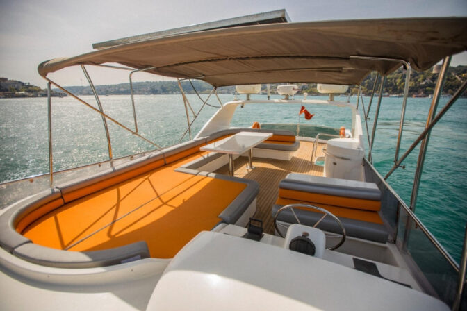 Corona Yat Turizm teknesinin geniş güneşlenme minderleri ve masaya sahip ferah üst güvertesi.