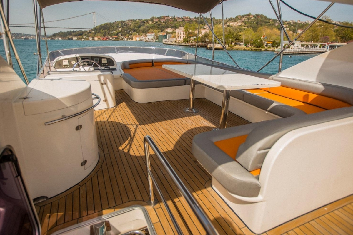 Corona Yat Turizm teknesinin İstanbul Boğaz Köprüsü manzaralı, turuncu minderli üst teras oturma alanı.